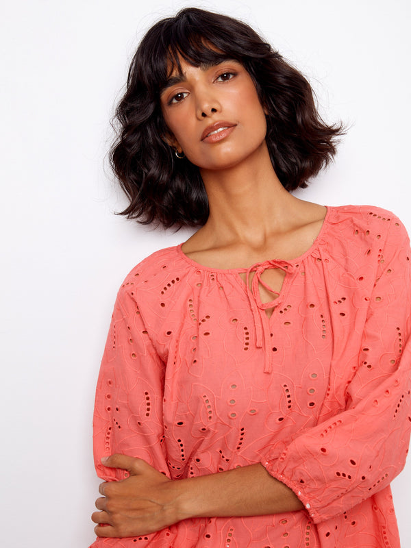 The scalloped hem of this coral blouse adds an elegant finish to the airy design by Charlie B.