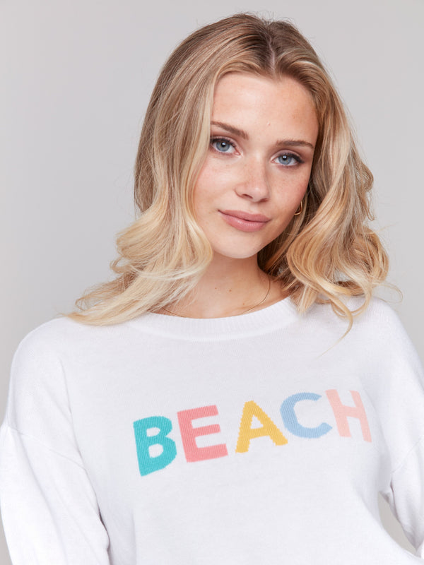 'BEACH' motif on cozy white knitwear piece by Charlie B.