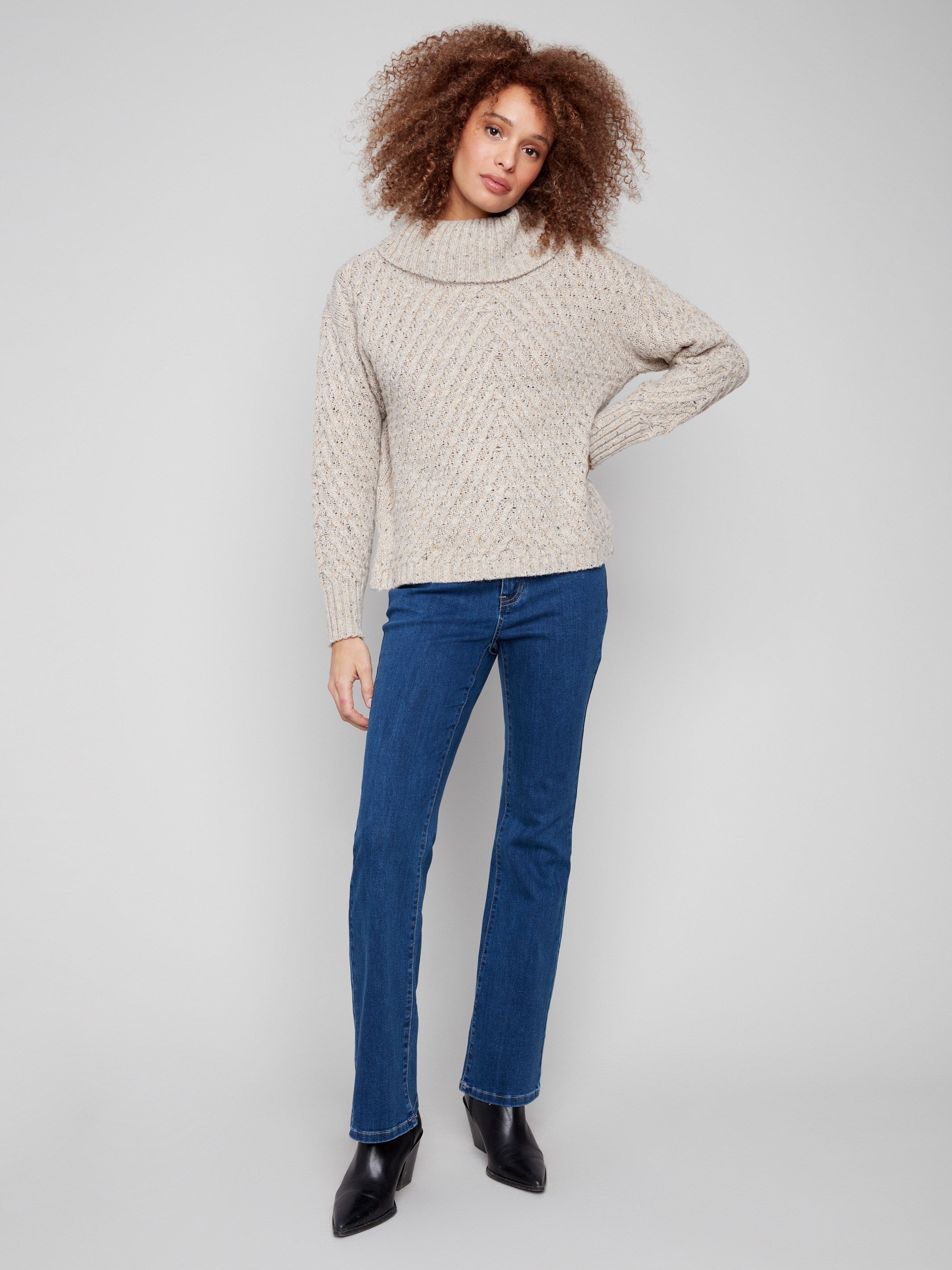 Oat-colored sweater showcasing a relaxed fit with intricate diagonal cable patterns and ribbed detailing by Charlie B.