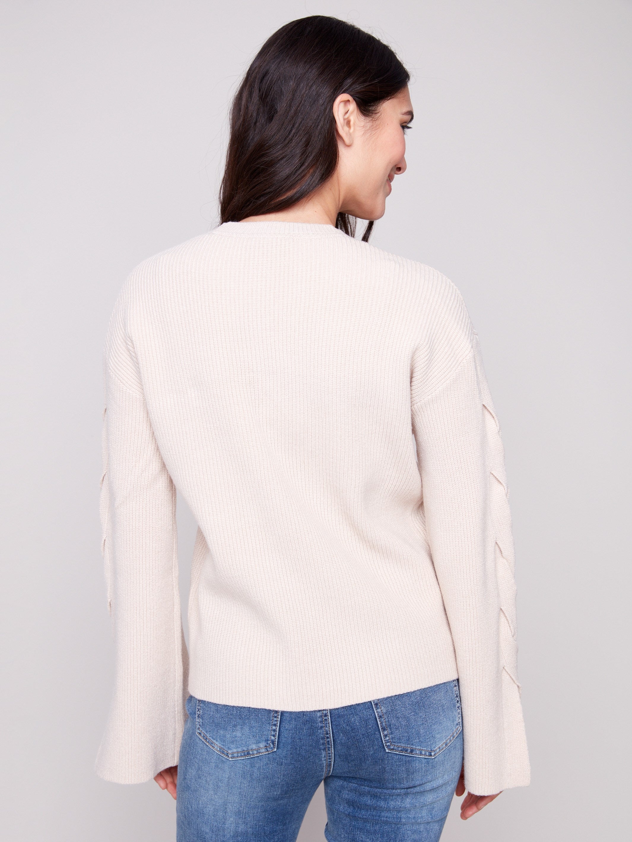 Soft oat sweater with drop shoulders and intricate sleeve design, offering both comfort and style by Charlie B.