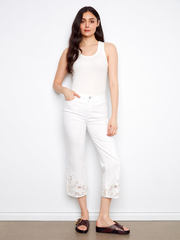 White cropped pants with a flared fit and intricate laser-cut lace hem, perfect for casual elegance by Charlie B.