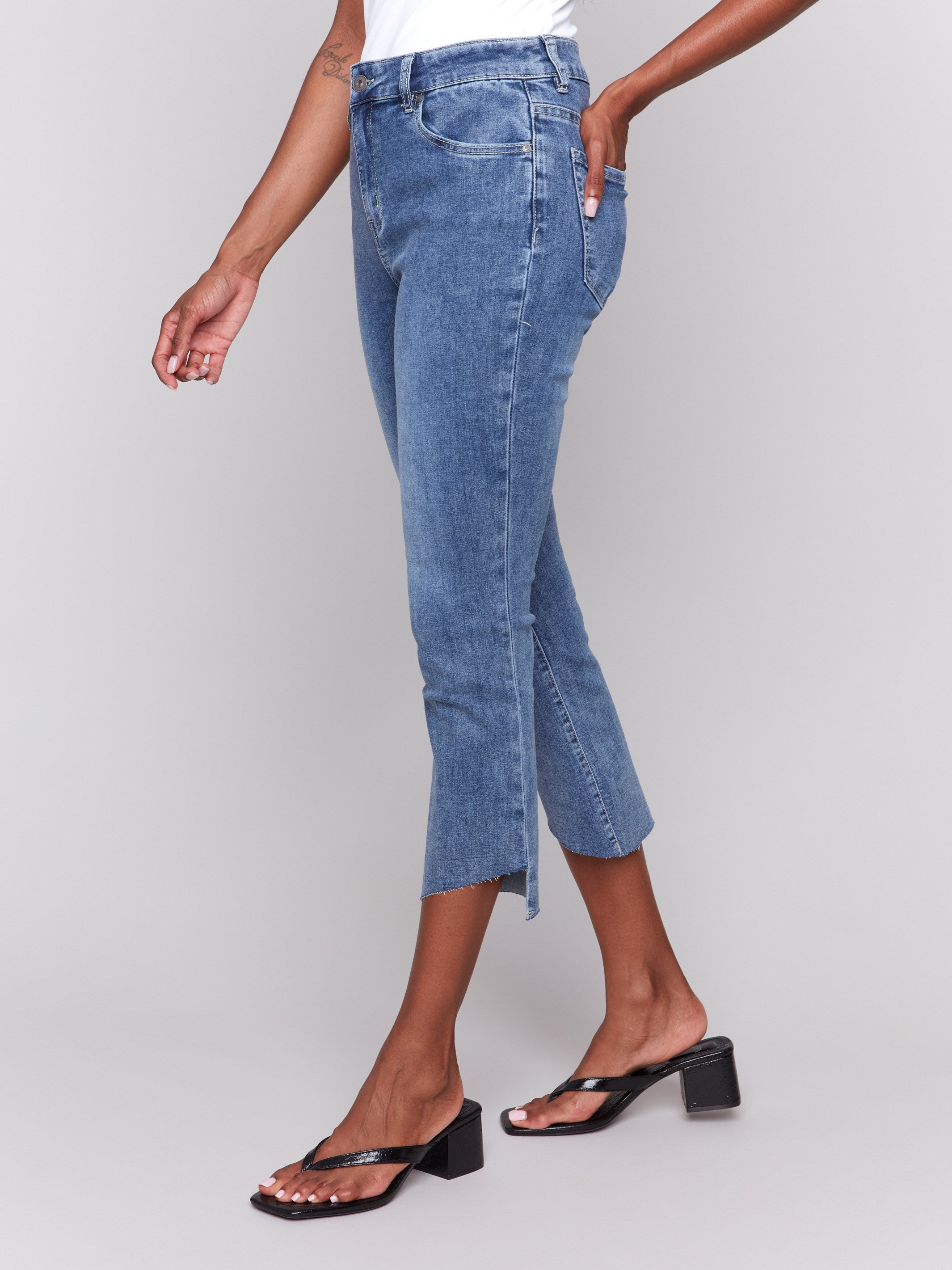 Blue jeans featuring an asymmetrical hem and stretch denim material by Charlie B.