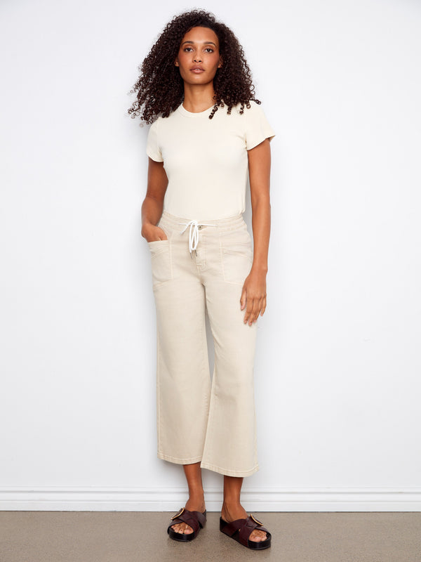 Beige wide leg twill pants featuring a cropped length and styled with casual sandals, perfect for summer days by Charlie B.