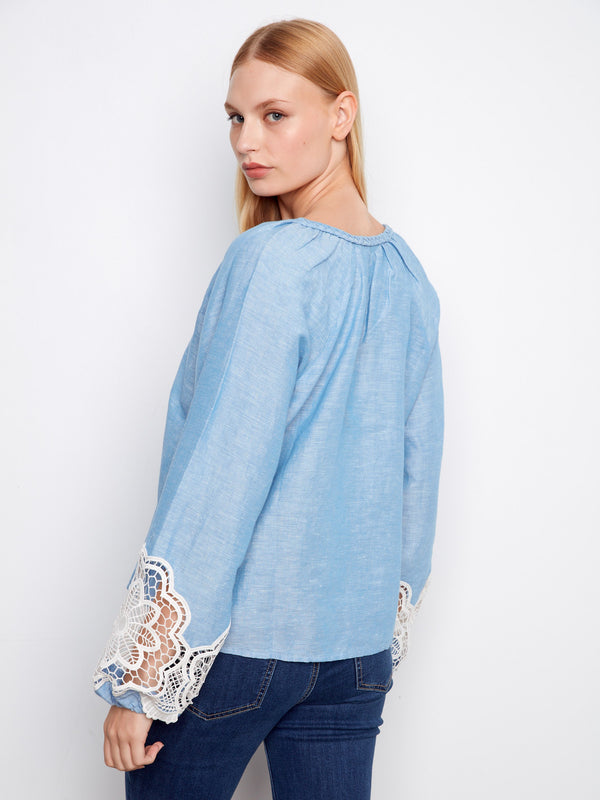 Stylish openwork lace details on the sleeves of this charming blue top add elegance. By Charlie B.