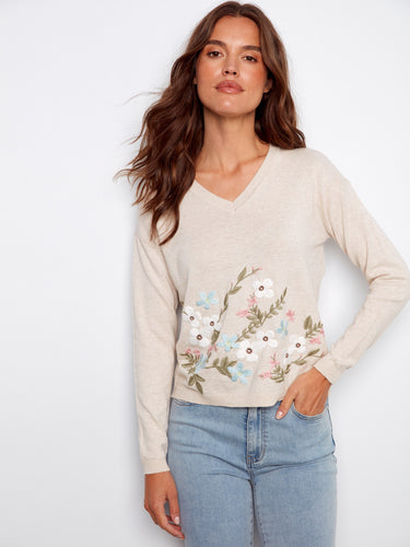 Elegant beige sweater showcasing intricate floral embroidery and a stylish V-neck, designed in 100% cotton by Charlie B.