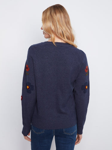 The cozy crew neck sweater is designed with attention to detail, showcasing vibrant floral embroidery on the sleeves. By Charlie B.