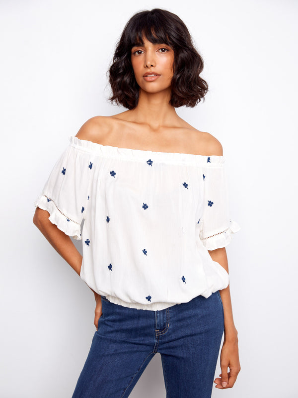 Elegant off-the-shoulder blouse with short flutter sleeves and blue floral details by Charlie B.