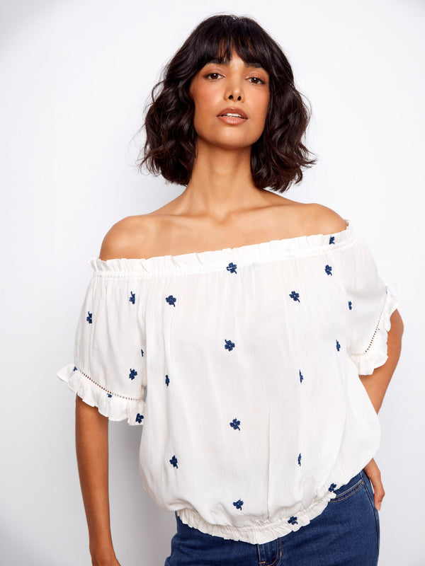 White blouse with delicate flutter sleeves and intricate blue embroidery by Charlie B.