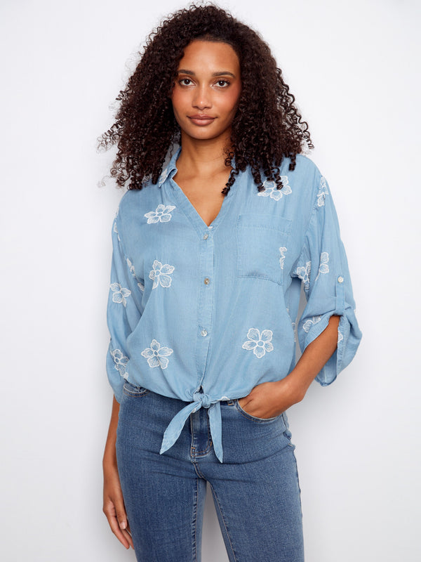 Blue blouse with floral embroidery and a collared V-neckline, highlighted by a chest pocket for added style by Charlie B.