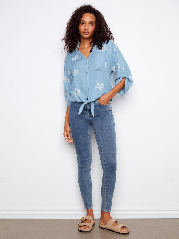 Elegant blue blouse featuring button-down front and floral patterns, complete with 3/4 roll-up sleeves by Charlie B.