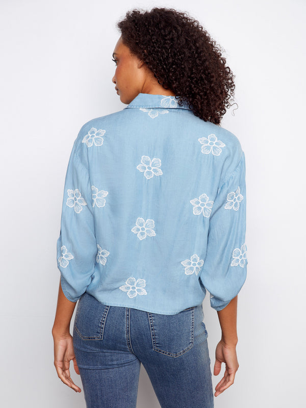 Light blue blouse featuring delicate floral embroidery on the back, adding elegance to any outfit by Charlie B.