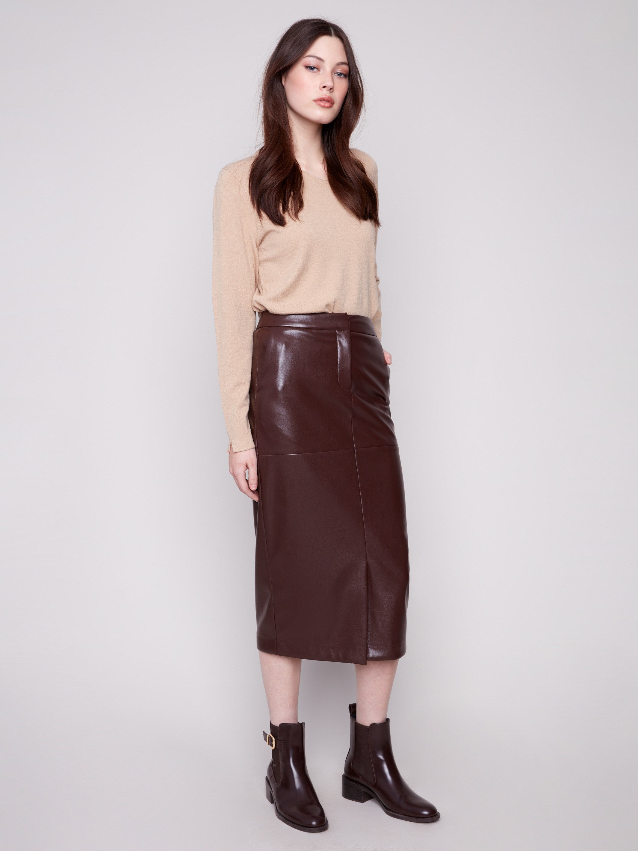 Cabernet faux leather midi skirt featuring side pockets, paired with a beige top and brown ankle boots by Charlie B.