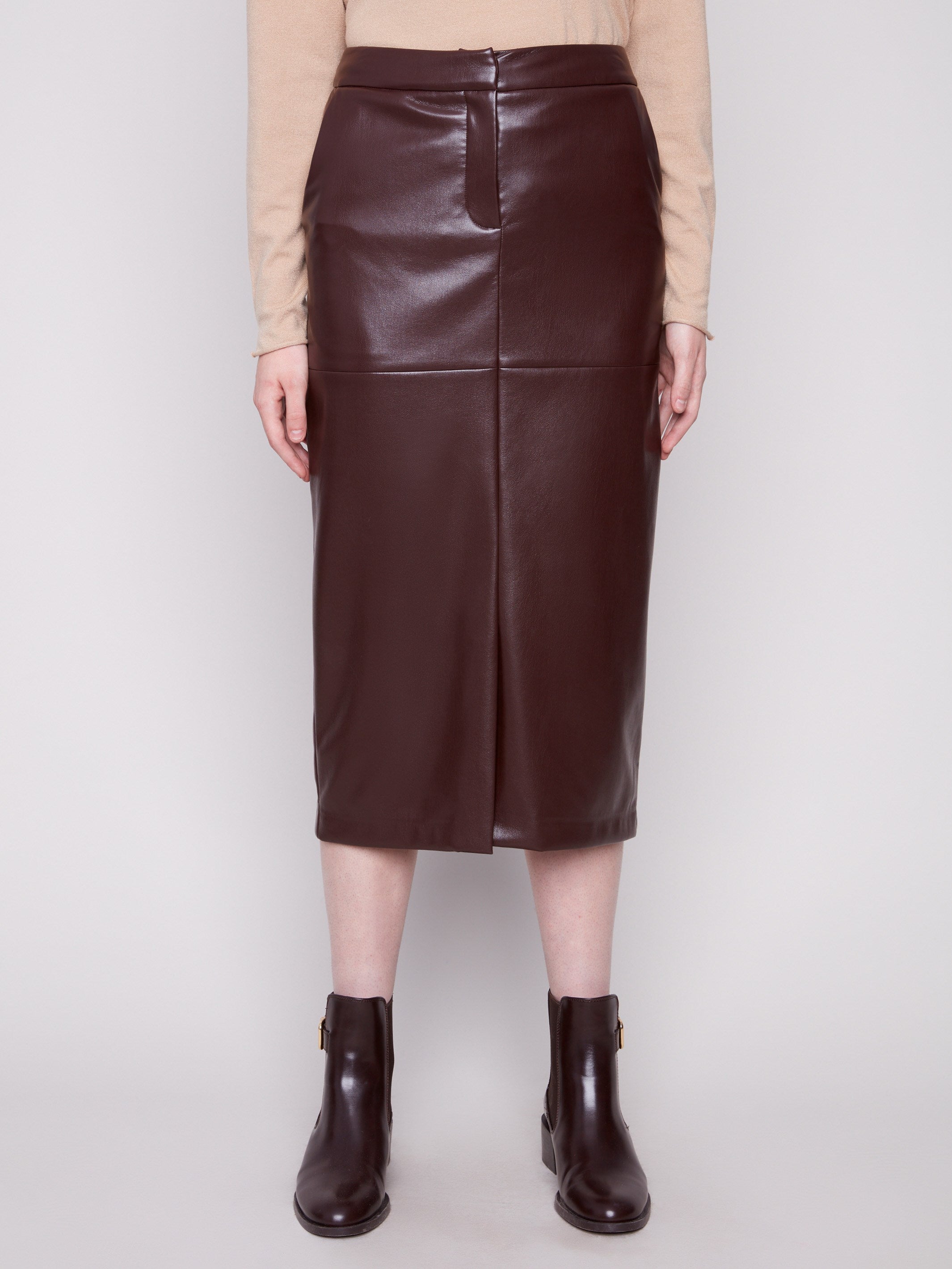 Sophisticated cabernet faux leather midi skirt with a slit front hem, styled with a beige top and brown boots by Charlie B.