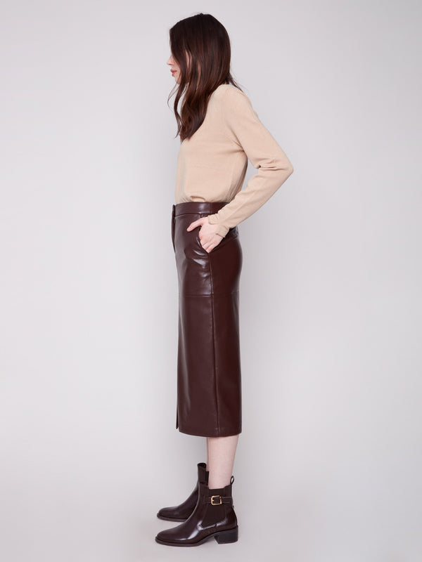 Elegant cabernet faux leather midi skirt in lined fabric, matched with a beige top and brown ankle boots by Charlie B.