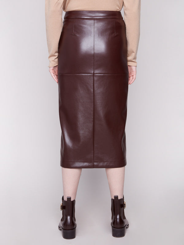 Chic cabernet faux leather midi skirt showcasing its sleek design, complemented by a beige top and brown ankle boots by Charlie B.