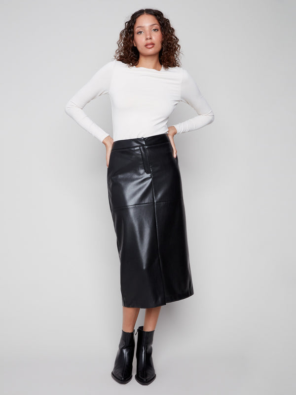 Black faux leather midi skirt featuring side pockets, paired with a white top and black ankle boots by Charlie B.