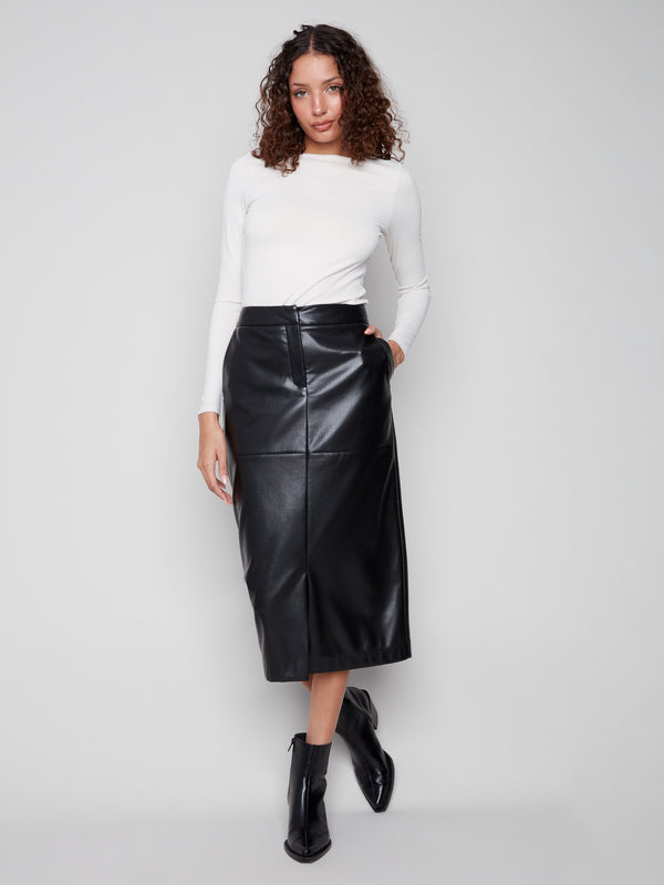 Elegant black faux leather skirt with a stylish slit front hem, matched with a white top and black boots by Charlie B.