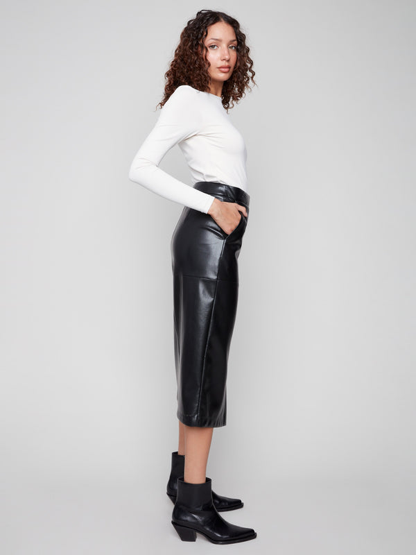Chic lined fabric midi skirt in black faux leather, styled alongside a white top and sleek ankle boots by Charlie B.