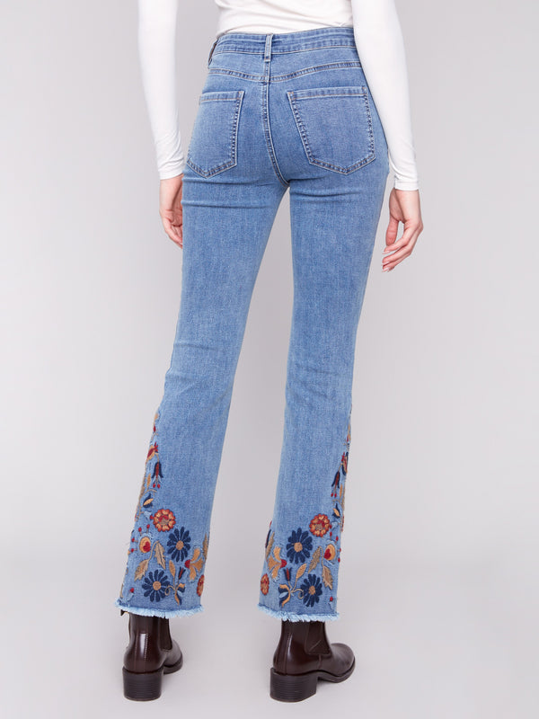 Five-pocket design blue jeans enhanced with beautiful floral embroidery for added flair by Charlie B.