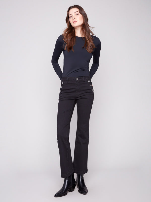 Black flare leg pants in long length featuring stretch twill fabric with stylish button accents by Charlie B.