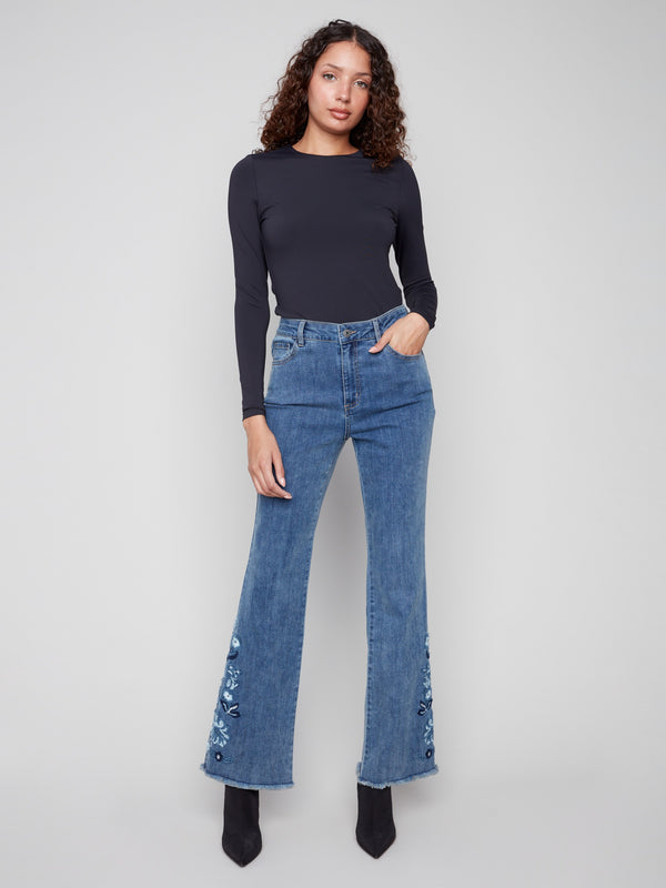 Medium blue jeans with a flare leg and floral embroidery, crafted in stretch denim for comfort by Charlie B.