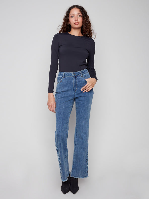 These five-pocket design jeans in medium blue offer both style and functionality with floral accents by Charlie B.