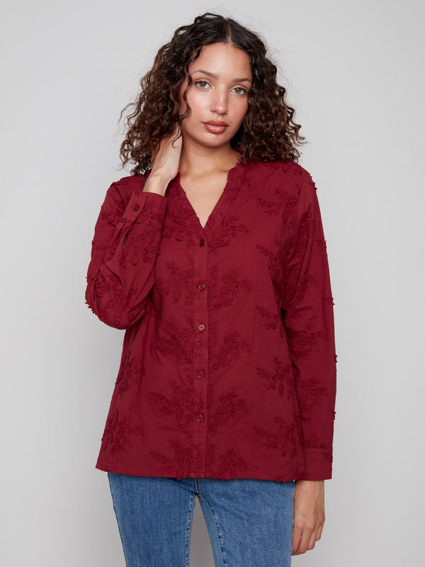 Elegant long-sleeve cabernet blouse with adjustable button cuffs and intricate floral details by Charlie B.