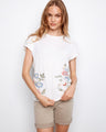 White top featuring floral embroidery and cap sleeves, crafted from 100% cotton for comfort by Charlie B.