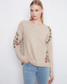 Beige sweater featuring long raglan sleeves adorned with colorful floral embroidery by Charlie B.
