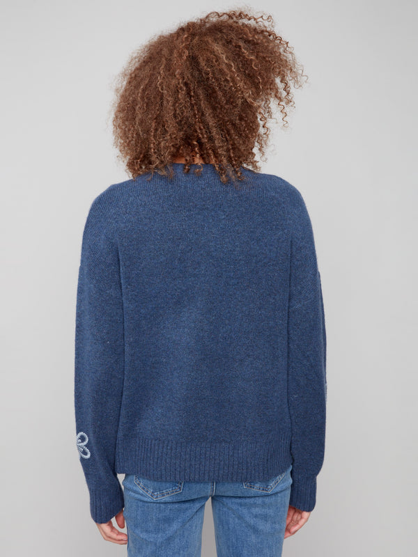 Soft heather denim sweater highlighted by ribbed hem and cuffs, complemented with floral embroidery by Charlie B.