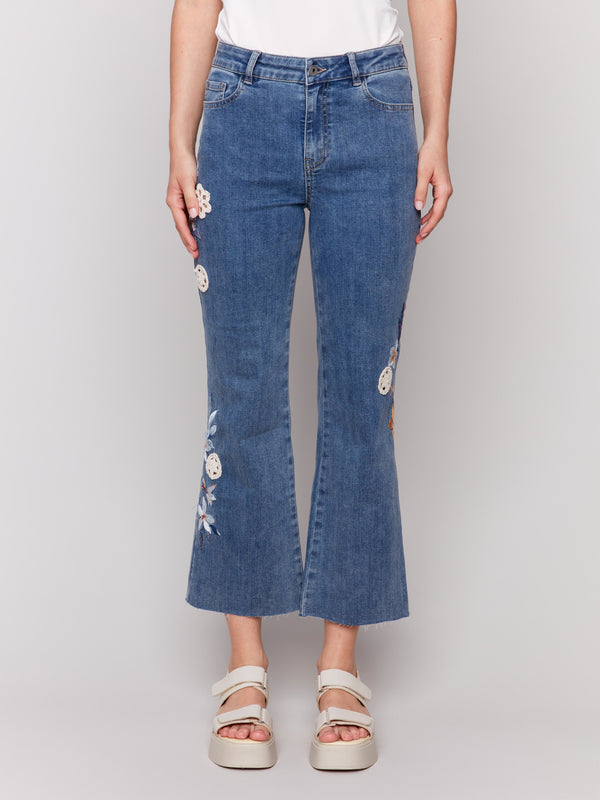 Jeans featuring floral embroidery and crochet accents in medium blue by Charlie B.