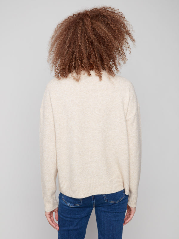 Cozy beige sweater showcasing drop shoulders and intricate floral jacquard detailing by Charlie B.