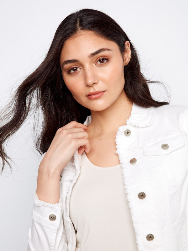 Classic white denim jacket with unique frayed detailing and functional button closure, ideal for layering by Charlie B.