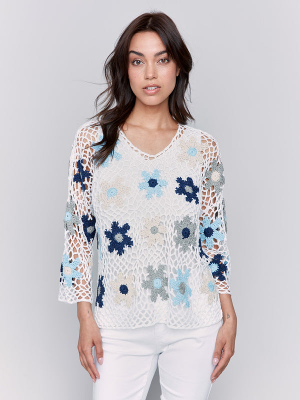 Blue floral crochet V-neck top with fishnet design, showcasing intricate hand crochet work and vibrant floral patterns by Charlie B.
