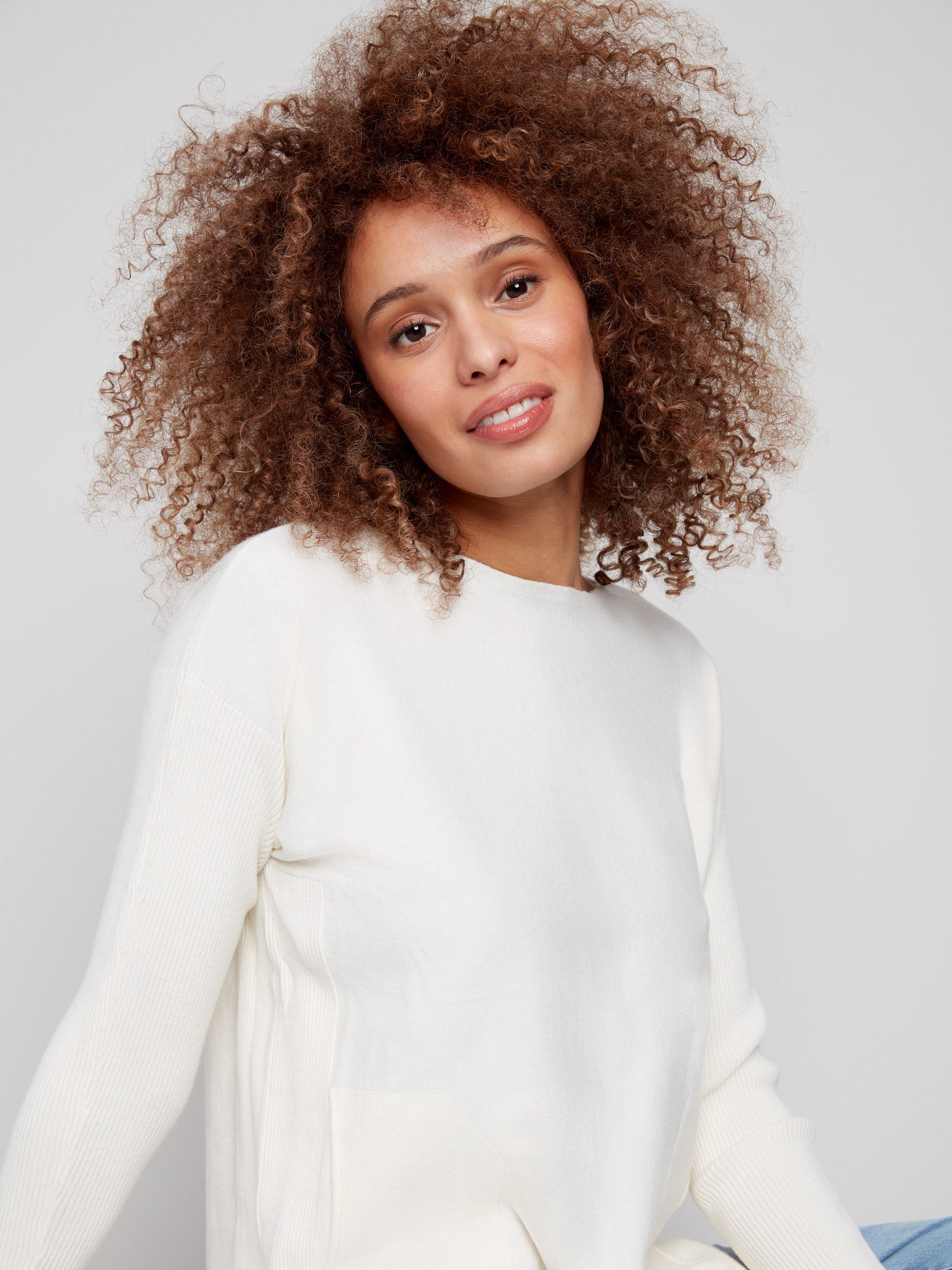 Stylish ecru sweater designed with convenient front pockets and rounded hem for added flair by Charlie B.