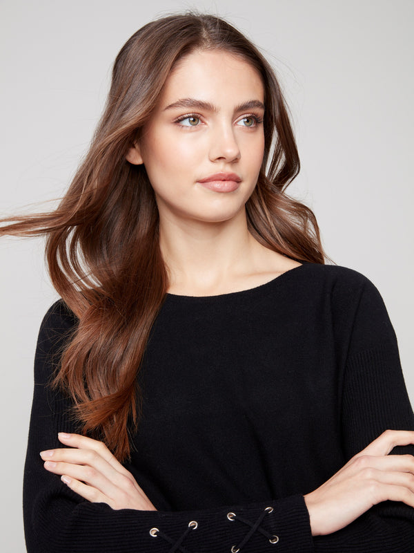 Elegant black knit sweater with eye-catching lace-up cuff details and stylish side pockets by Charlie B.