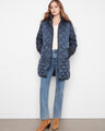 Quilted coat featuring a removable hood, paired with jeans and boots. Elegant and versatile for cold weather by Charlie B.