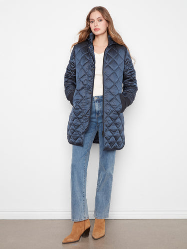 Quilted coat featuring a removable hood, paired with jeans and boots. Elegant and versatile for cold weather by Charlie B.