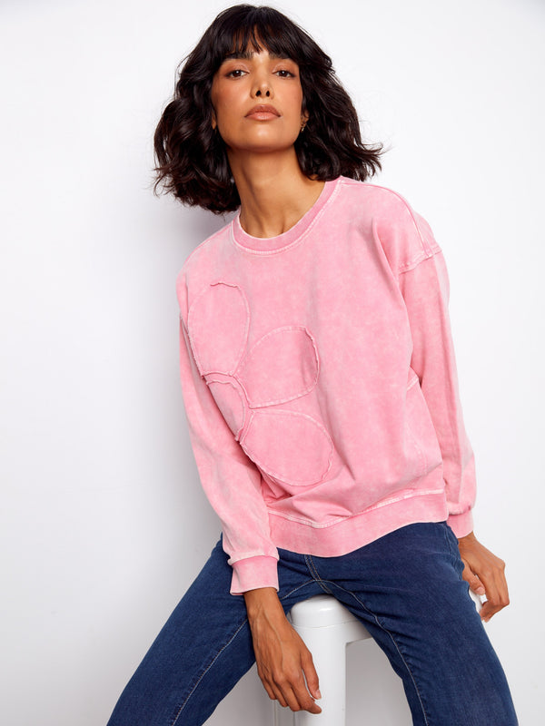Fashionable pink sweatshirt highlighting the intricate flower applique design that stands out effortlessly by Charlie B.