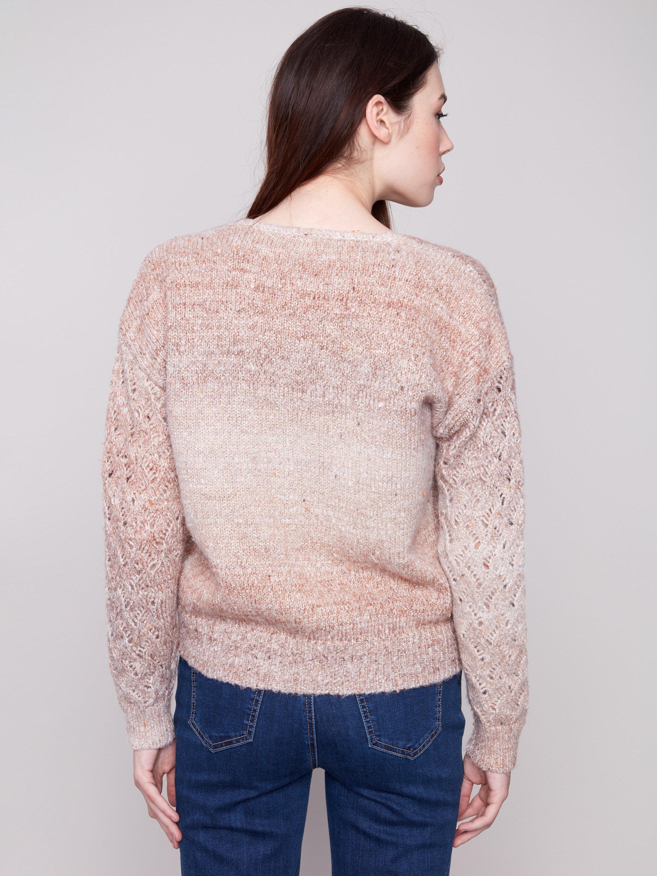 Elegant sweater in latte hue showcasing intricate open knit sleeves, perfect for layering by Charlie B.