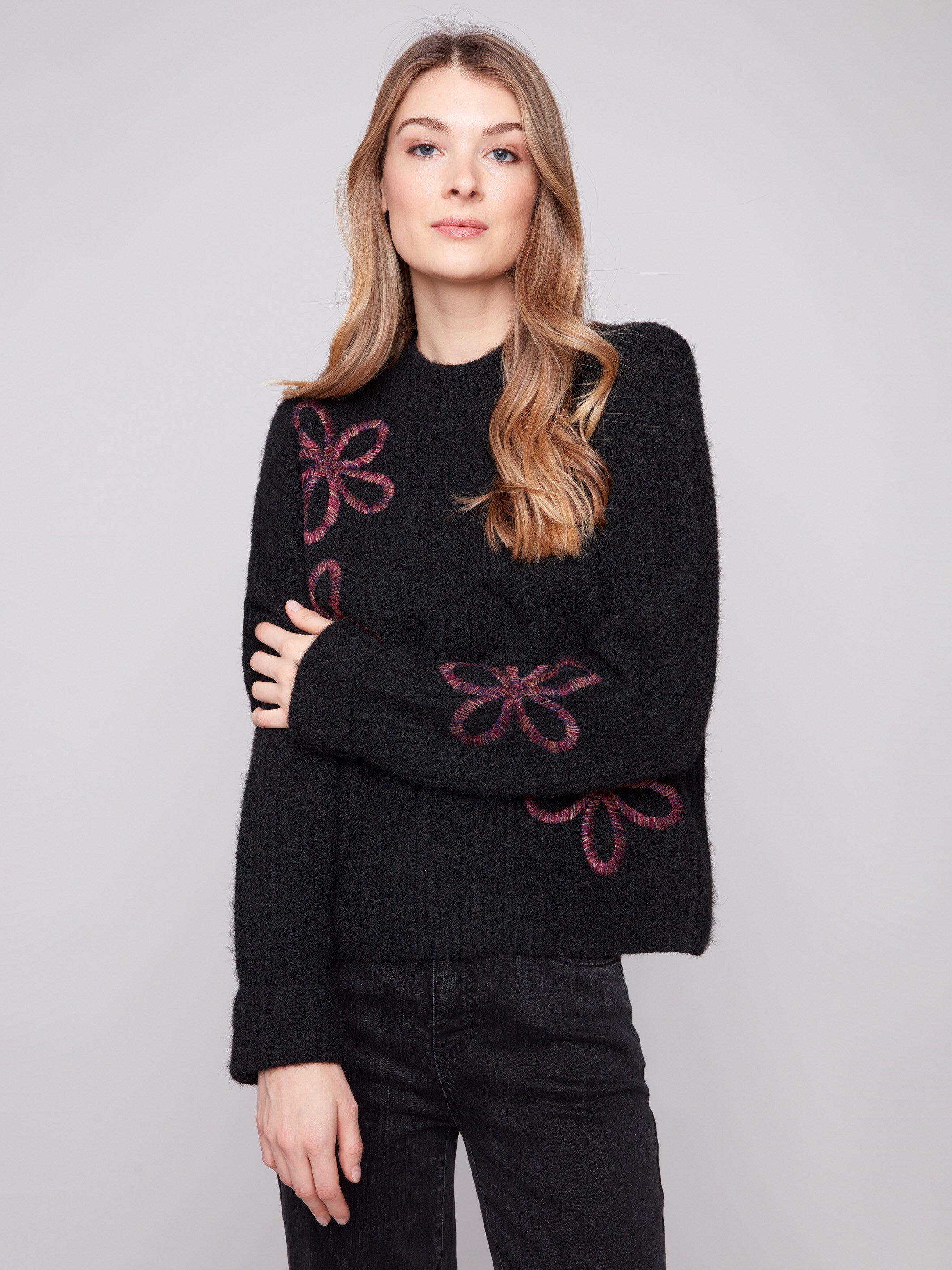 Black sweater featuring a mock neck and floral soutache embroidery, highlighting its relaxed fit by Charlie B.