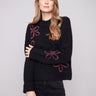 Black sweater featuring a mock neck and floral soutache embroidery, highlighting its relaxed fit by Charlie B.