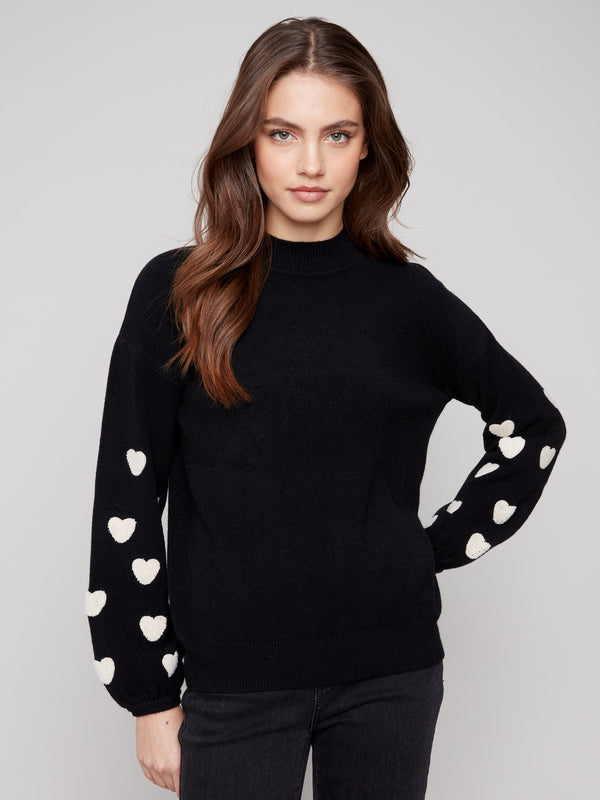 Elegant black sweater with a chic mock neck design, featuring white heart details on sleeves by Charlie B.