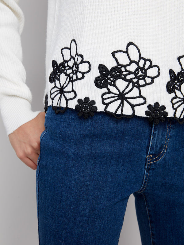Detailed view of the ecru sweater's exquisite black floral lace hem design by Charlie B.