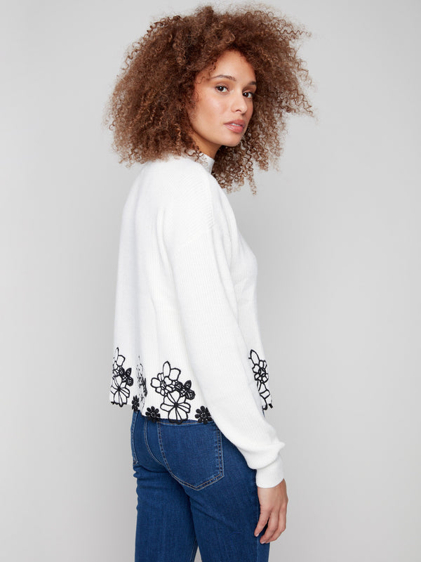 Ecru sweater showcasing a drop shoulder style paired with charming black floral lace trim by Charlie B.