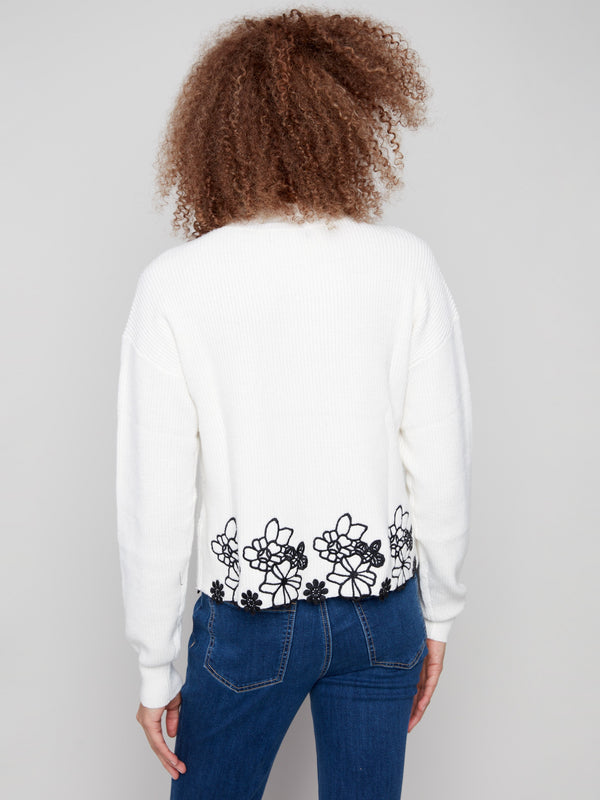 Back view of hip-length ecru sweater highlighting its unique black floral lace detail by Charlie B.