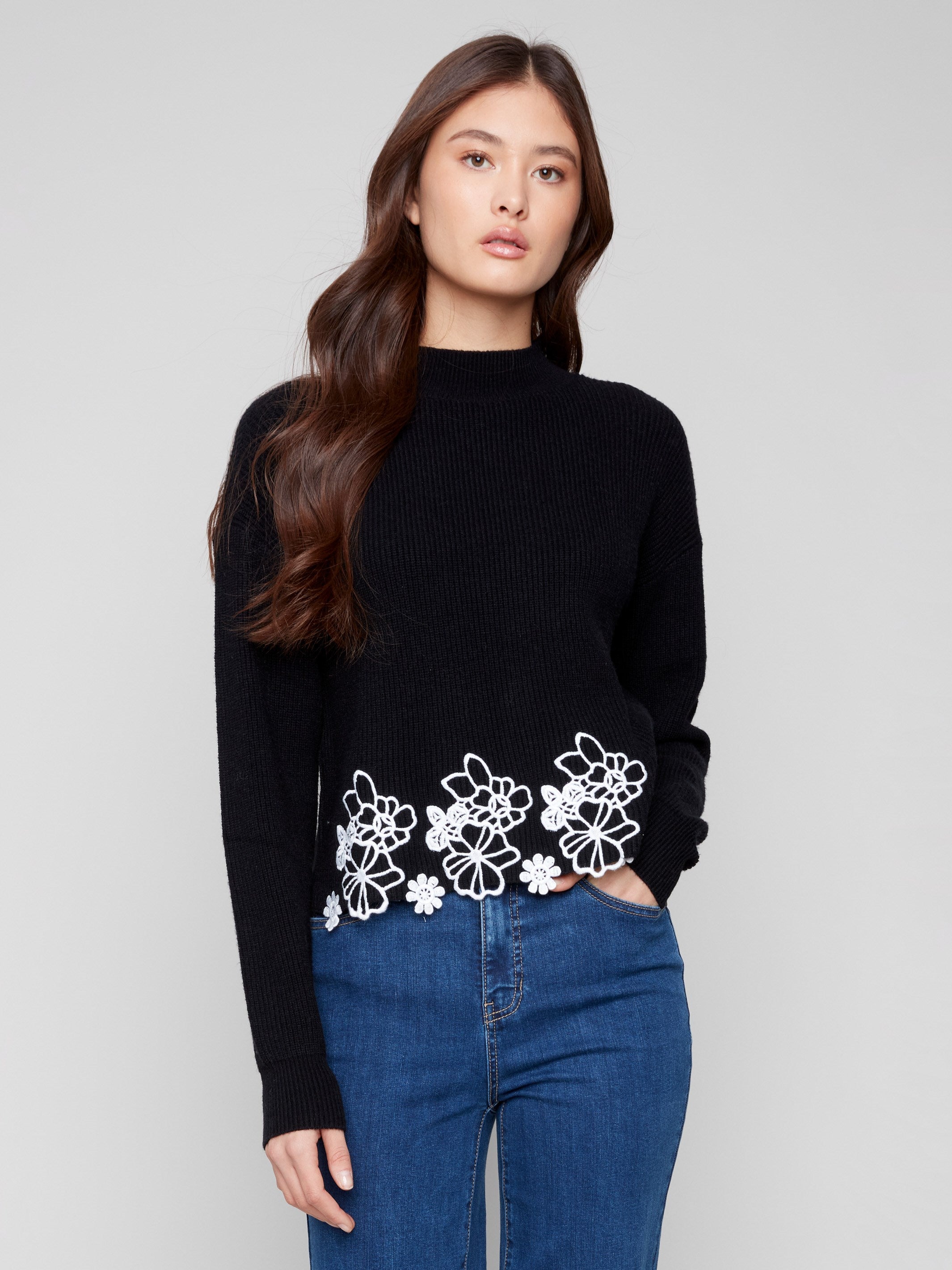 Black sweater featuring a mock neck and elegant drop shoulder design, highlighted by floral lace hem by Charlie B.