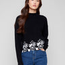 Black sweater featuring a mock neck and elegant drop shoulder design, highlighted by floral lace hem by Charlie B.