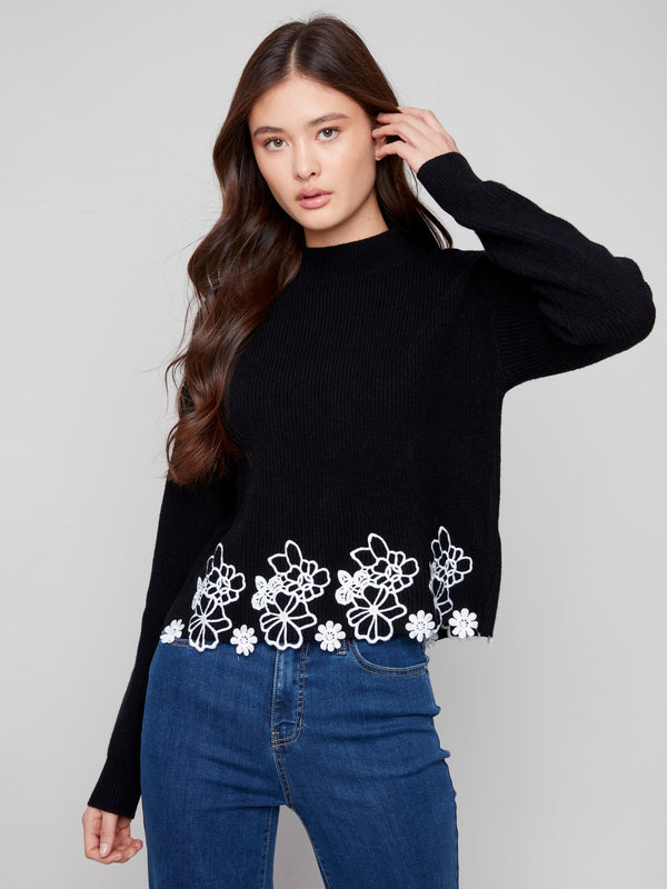 Sophisticated black sweater with a charming floral lace hem and hip-length cut, perfect for versatile styling by Charlie B.