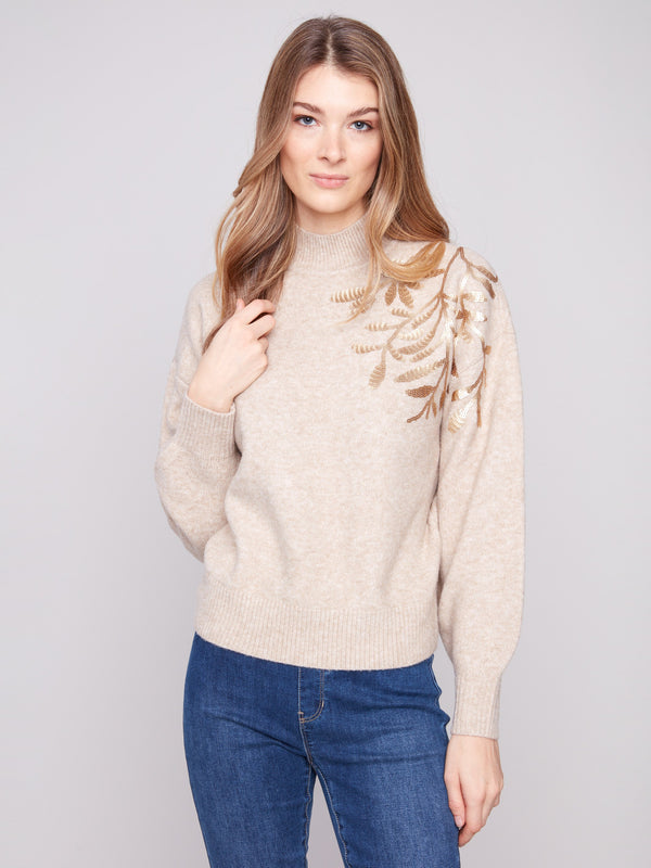 Heather oat sweater with a chic mock neck, showcasing elegant floral embroidery and knit cuffs by Charlie B.
